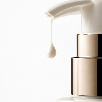Primer plano de un envase cosmético blanco con bomba dosificadora dorada, dispensando una gota de loción.
